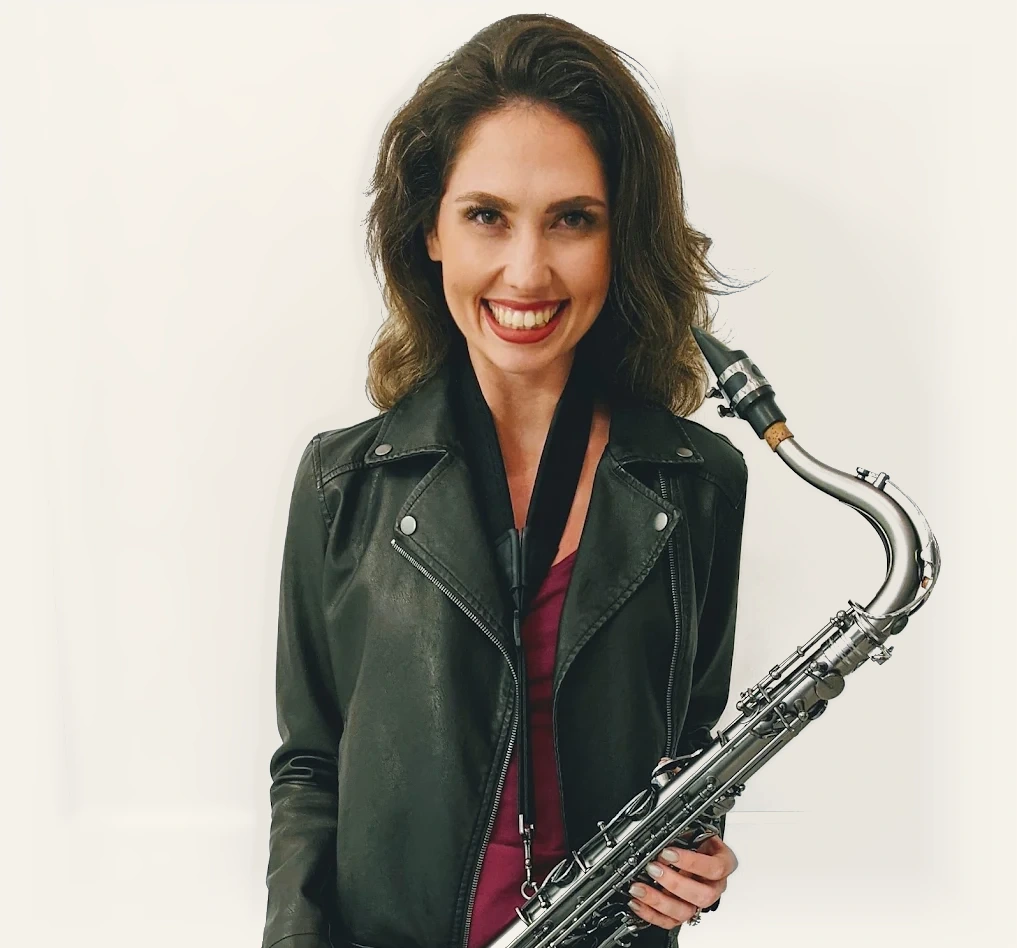 Amy Cyr smiling warmly while holding her tenor saxophone